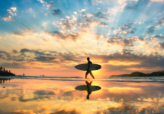 surfer-walking-on-the-beach-at-sunset-img